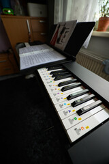 A close‑up of an electronic piano with attached sheet notes in an interior.