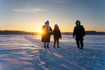 Mother, Son and Daughter Walking on Snowy Icy Lake at Sunset, Happy Winter Family Outing
