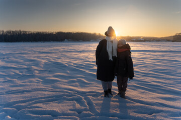 Mother and Daughter Walking on Frozen Icy Lake at Sunset, Winter Family Bonding