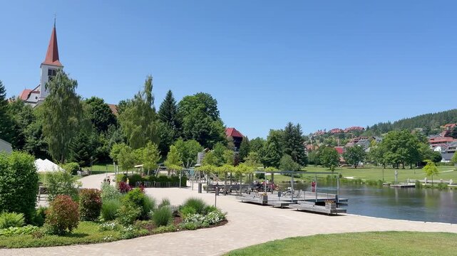 Schonach im Schwarzwald, Germany - 06 20 2025: The Kurpark of Schonach with its lake and the church in the background.