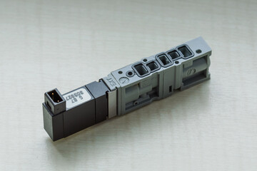 A small pneumatic valve with a coil lying on a table.