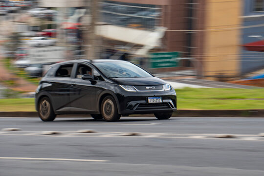 Black BYD Dolphin front view panning shot, Electric hatchback driving on urban road