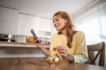 Woman using phone saving money with piggy bank