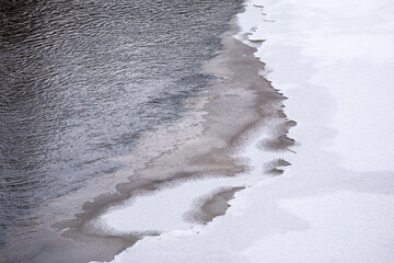 Melting River Ice Edge Showing Seasonal Transition Between Water And Snow