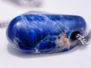 A detailed close‑up of a sodalite stone with a hole for a chain.