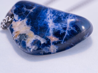 A detailed close‑up of a sodalite stone with a hole for a chain.