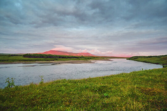 The evening landscape of the tundra, the fast river, the last rays of the sun illuminated the mountain in the distance.