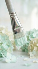 Paintbrush dripping mint green paint over delicate hydrangea flowers