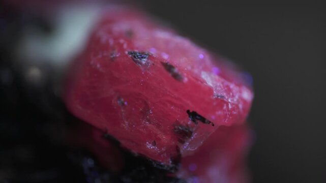 Macro image of corundum crystal exhibiting red fluorescence captured via microscope objective at 2.4&times; magnification with 15 mm field of view. Naturally developed surface and emission