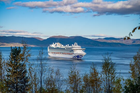 Large cruise vessel navigating scenic Norwegian fjord waters surrounded by autumn mountains. Perfect for travel marketing, cruise tourism and Arctic Norway destination content.