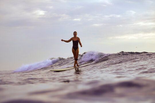 Woman Gliding On Wave At Golden Hour, Capturing Cinematic Sunset Vibe With Poised Stance And Warm Reflections