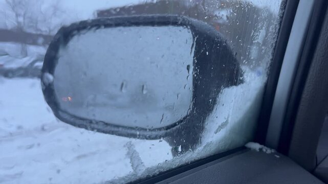 Frosted car window blocking side mirror view after winter storm