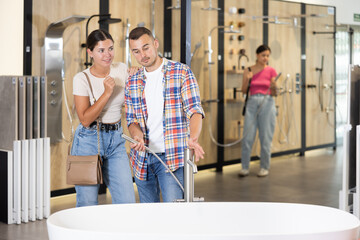 Fototapeta premium Couple of young man and woman choosing bath in hardware store