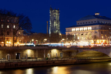 Paris city center by night with embankments of river Seine and illuminated street and historical Saint Jacques Tower in the foreground.Paris . France.