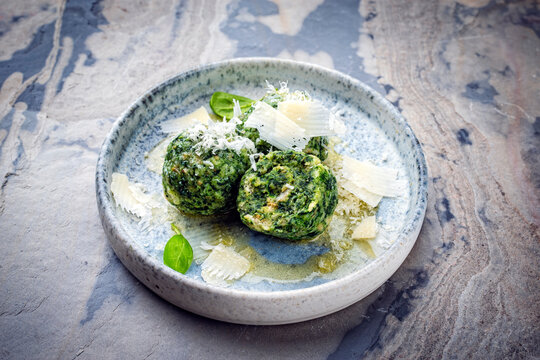 Artisan homemade Austrian spinatkn&ouml;del - bread knodel dumpings with melted butter and parmesan served as close-up on a design plate