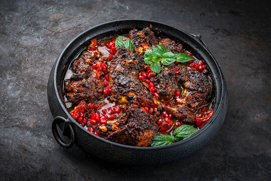 Traditional authentic Persian khoresh fesenjan - chicken stew with walnut and pomegranate sauce served as close-up in a design pan
