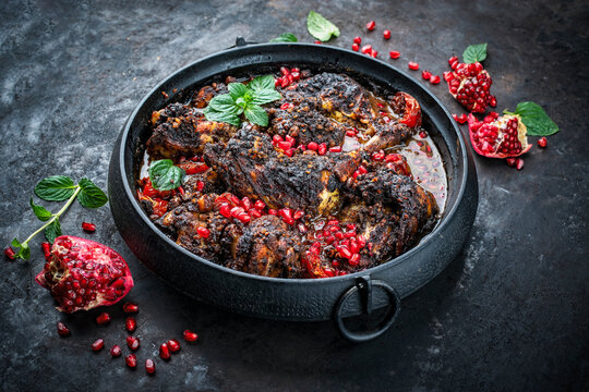  Traditional authentic persian khoresh fesenjan - chicken stew with walnut and pomegranate sauce served as close-up in a cast iron design pot