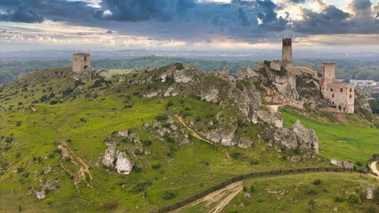 Castle ruins in Olsztyn near Częstochowa captured in golden hour light, aerial drone view over limestone rocks and historic fortress in Poland © Konrad Kerker