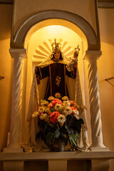 Statue of Virgin Mary with Child Jesus in an Ornate Church Niche, Catholic Madonna and Child Figure with Crowns and Floral Offerings, Sacred Religious Altar Featuring Virgin Mary and Infant Jesus 
