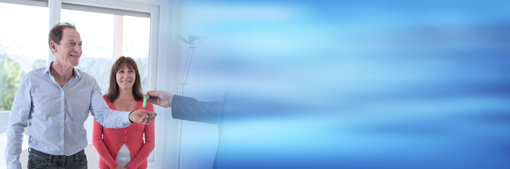 Happy couple getting house keys from realtor; panoramic banner