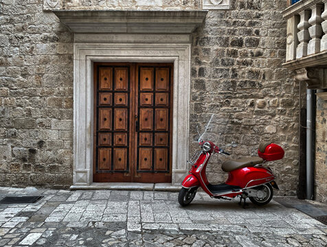 Roter Motorroller neben einer Haust&uuml;r in einer alten Mauer in Trogir, KroatIen