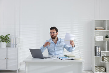 Obraz premium Man suffering from heat at table near white wall indoors, space for text