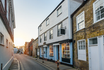 Traditional brick buildings and shops along a narrow street in a city centre at sunset in spring © alpegor