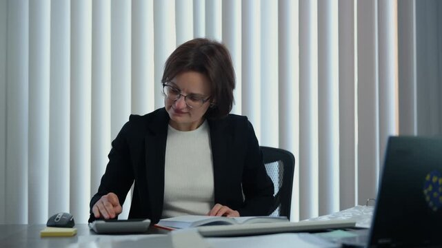 Business woman accountant making calculations of financial data sheet with calculator and computer., Business and financial concept.