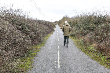 Obraz premium A man walking in the road overgrown with blackberries. 