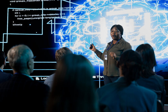 AI concept presentation on stage showing artificial intelligence technology and machine learning, african american speaker discuss funding with potential investors in conference hall.