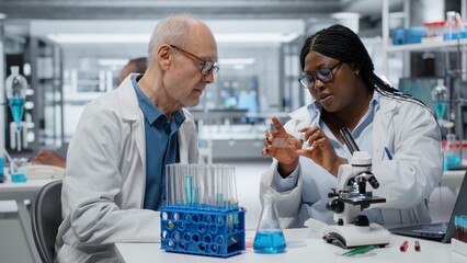 Team of microscopists reviewing patient biopsy slide to detect abnormal cellular growth....