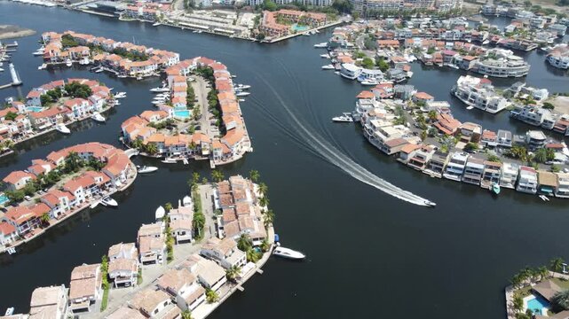 Cinematic aerial over Pueblo Viejo, Lecher&iacute;a, revealing luxury waterfront homes, navigable canals and boats under bright Caribbean skies.