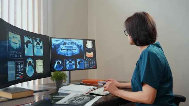 Dentist reviewing and describing dental scans examining them on monitors and paper documents, modern clinic workspace and medical imaging analysis concept.