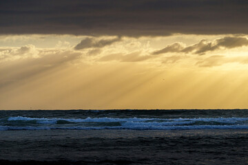 Obraz premium Dark cloudy sky and sea separated by golden hour moody sky