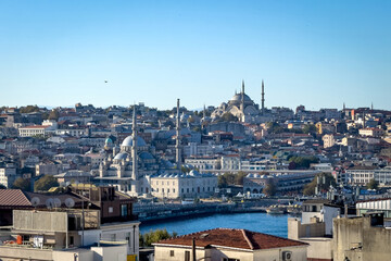 Fototapeta premium View over the Golden Horn toward Istanbul’s historic peninsula: Yeni Camii at left and Nuruosmaniye Camii up the hill, clear blue sky and calm water in bright daylight