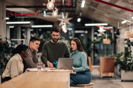 Diverse team collaborating on laptop in modern office