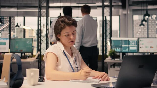 Frustrated businesswoman tearing and crumpling paper after writing mistake at desk. Handwritten notes, ripping pages due to failed attempt and writing error reflect creative block and setback.