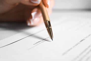Woman signing Last Will and Testament at table, closeup