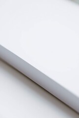 A close-up view of a clean white surface with a diagonal grey edge and a subtle shadow extending across the lower portion