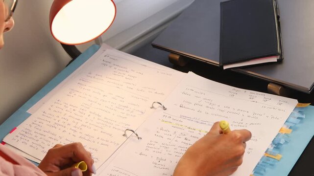 Close-up of a woman reading and highlighting her notes at a desk. The image conveys concentration, learning, academic focus, and productive study habits in a modern educational setting.
