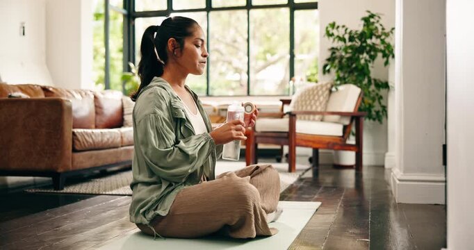 Yoga mat, drinking and woman with water in home for hydration, wellness and health after exercise. House, rest and person with liquid, minerals and bottle for recovery, thirst and active hobby