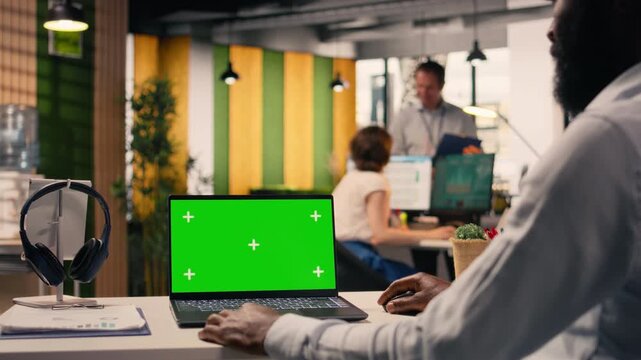 Green screen laptop, black businessman, in a modern office, review visual data, charts and graphs. Performance metrics, KPI dashboard, forecasting reports, corporate strategy, global business.