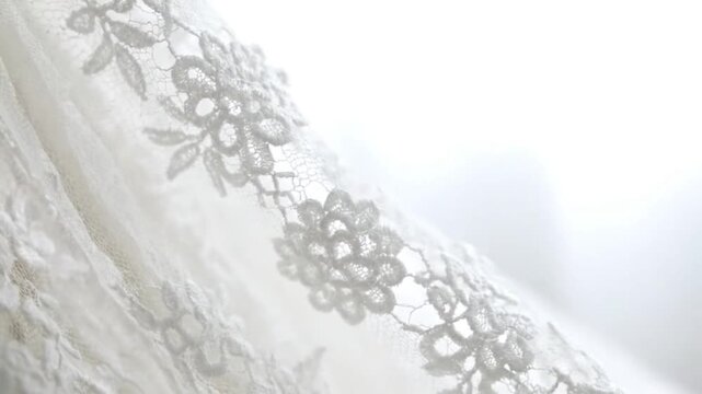 Close-up of a white wedding veil with intricate floral embroidery on a soft, blurred background.