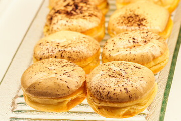 Gourmet Glazed Doughnuts with Chocolate Powder Sprinkles on Glass Tray, Close up of Fresh Sweet Pastry Dessert in Cafe, Delicious Creamy Donut Selection for Gastronomy and Culinary Background
