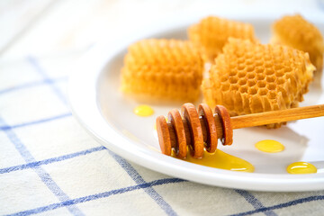Sweet golden bee honey dripping out of honeycomb in a plate, selective focus.