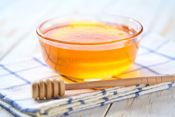 Glass bowl with sweet honey on а white table, selective focus.