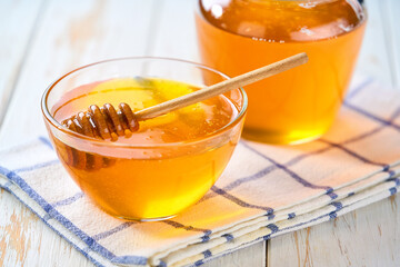 organic honey in a glass bowl on a white table, selective focus.