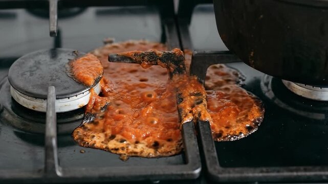 Food spills over from pot on stovetop during cooking. Kitchen appears busy with cookware present. Concept of home cooking, meal prep, kitchen safety