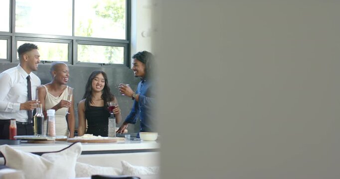 Camera pulling back, African American friends raising glasses, toasting at kitchen island
