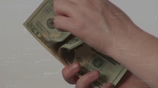 Hands starting thumb slide, flipping and fanning twenty-dollar bills for counting on gray backdrop